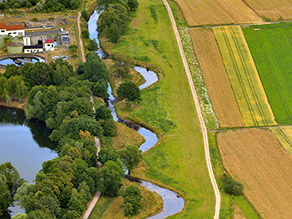 Luftaufnahme der renaturierten Kahl flussaufwärts, die sich angrenzend an Wiesenflächen und von Geh- und Radwegen begleitet durch die Landschaft schlängelt. Neben den Wegen Seen und Ackerflächen. Luftaufnahme der renaturierten Kahl flussaufwärts, die sich angrenzend an Wiesenflächen und von Geh- und Radwegen begleitet durch die Landschaft schlängelt. Neben den Wegen Seen und Ackerflächen.