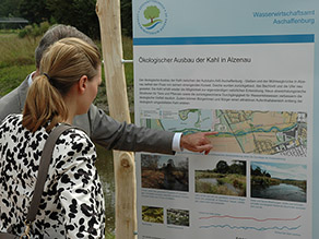 Zwei Personen vor einer Infotafel zum Ökologischen Ausbau der Kahl in Alzenau, die am Ufer eines Flusses steht. Zwei Personen vor einer Infotafel zum Ökologischen Ausbau der Kahl in Alzenau, die am Ufer eines Flusses steht.