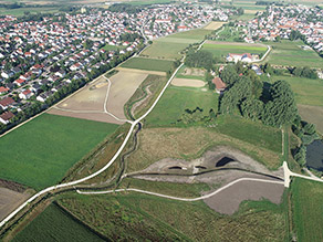 Luftaufnahme des letzten Bauabschnittes: Ein neuer Geh- und Radweg verläuft entlang eines renaturierten Baches. Wiesen- und Ackerflächen grenzen daran an. Im Hintergrund Siedlungsbereiche. Luftaufnahme des letzten Bauabschnittes: Ein neuer Geh- und Radweg verläuft entlang eines renaturierten Baches. Wiesen- und Ackerflächen grenzen daran an. Im Hintergrund Siedlungsbereiche.
