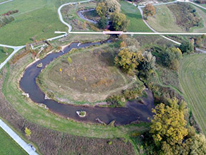 Luftaufnahme einer Flussschleife des Roten Mains mit begleitendem Geh- und Radweg und einer Fußgängerbrücke im Hintergrund. Kleine Buhnen, Inseln und Totholzansammlungen sowie Gewässeraufweitungen sorgen für Struktur und eine erhöhte Breiten- und Tiefenvarianz. Luftaufnahme einer Flussschleife des Roten Mains mit begleitendem Geh- und Radweg und einer Fußgängerbrücke im Hintergrund. Kleine Buhnen, Inseln und Totholzansammlungen sowie Gewässeraufweitungen sorgen für Struktur und eine erhöhte Breiten- und Tiefenvarianz.