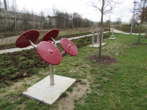 Fitnessgeräte stehen entlang eines Geh- und Radweges. Im Hintergrund ein Fluss. Fitnessgeräte stehen entlang eines Geh- und Radweges. Im Hintergrund ein Fluss.