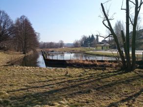 Ein strukturarmer Fluss mit Ufermauern zur beidseitigen Ufersicherung und einem angrenzenden Teich. Ein Steg führt über das Gewässer. Ein strukturarmer Fluss mit Ufermauern zur beidseitigen Ufersicherung und einem angrenzenden Teich. Ein Steg führt über das Gewässer.