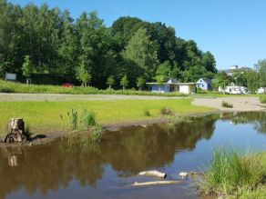 Ein Fluss mit sehr flachen Ufern und daran angrenzenden Kies- und Wiesenflächen. Im Hintergrund ein Wohnmobilstellplatz. Ein Fluss mit sehr flachen Ufern und daran angrenzenden Kies- und Wiesenflächen. Im Hintergrund ein Wohnmobilstellplatz.