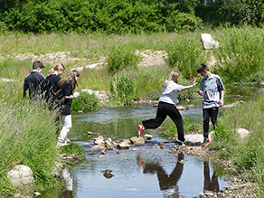 Kinder überqueren den renaturierten Selbbach an einer Furt aus Steinen Kinder überqueren den renaturierten Selbbach an einer Furt aus Steinen