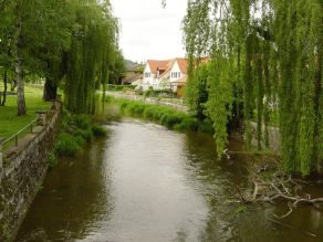 Ufermauern bilden ein Kastenprofil und trennen einen Fluss von angrenzenden Grünflächen und Wohnbebauung. Ufermauern bilden ein Kastenprofil und trennen einen Fluss von angrenzenden Grünflächen und Wohnbebauung.