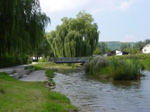 Sitzstufen zum Verweilen an dem abgeflachten Ufer eines Flusses mit Inselzone und neuer Fußgängerbrücke im Hintergrund. Sitzstufen zum Verweilen an dem abgeflachten Ufer eines Flusses mit Inselzone und neuer Fußgängerbrücke im Hintergrund.