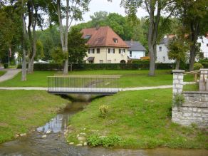 Der Webbach (Seitengewässer der Sulz) fließt durch eine Grünanlage mit Fußgängerbrücke und mündet in einen Fluss. Im Hintergrund Wohnbebauung. Der Webbach (Seitengewässer der Sulz) fließt durch eine Grünanlage mit Fußgängerbrücke und mündet in einen Fluss. Im Hintergrund Wohnbebauung.