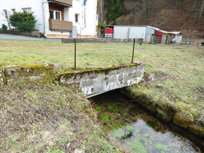 Ein Bach fließt aus einem Durchlass.