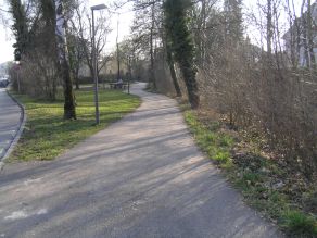 Ein Geh- und Radweg verläuft entlang eines Baches. Die Uferböschungen sind dicht bewachsen und ermöglichen keine Sicht auf das Gewässer. Ein Geh- und Radweg verläuft entlang eines Baches. Die Uferböschungen sind dicht bewachsen und ermöglichen keine Sicht auf das Gewässer.