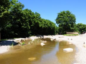 Blick auf den neuen Würm Durchstich. Flachere und tiefere Stellen zeichnen sich durch die Wasseroberfläche ab. Große Steine sind als Sitzgelegenheit und zur Strukturanreicherung in und neben der Wasserfläche verteilt. Blick auf den neuen Würm Durchstich. Flachere und tiefere Stellen zeichnen sich durch die Wasseroberfläche ab. Große Steine sind als Sitzgelegenheit und zur Strukturanreicherung in und neben der Wasserfläche verteilt.