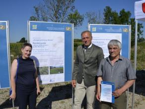 Die Preisträger und MD Dr. Detsch stehen links und rechts neben dem Preisträgerplakat. Eine Person hält eine Urkunde in der Hand.