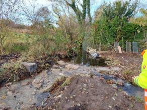 Rauhe Rampe im Bach aus Wasserbausteinen und Kies. Das Wasser fließt ohne abgelösten Wasserstrahl über die Rampe und ist durchgängig.