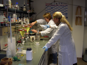 Zwei Mitarbeiterinnen in einem chemischen Labor. Auf dem Labortisch sind chemische Apparaturen aufgebaut.