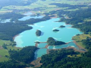 Luftbild der türkisleuchtenden Osterseen mit dunkelgrünen Wäldern und hellgrünen Wiesen.