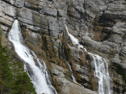 Aus einer Karsthöhle tritt an einer Felswand wasserfallartig Grundwasser aus.