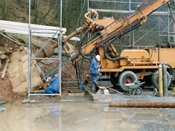 Aufnahme eines Bohrgerätes im Einsatz. Das Bohrgestänge geht schräg in einen Hang.