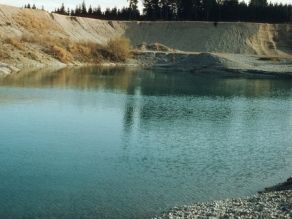 Blick auf eine kleinen See aus anstehendem Grundwasser, der durch Kiesabbau entstanden ist.