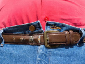 Eine zu enge Jeans wird von einem Gürtel zusammen gehalten.