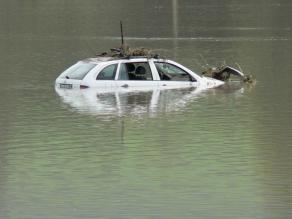 Pkw im Hochwasser. Der Wasserpegel reicht bis zu den Fenstern. Mitgeschwemmtes Material hat sich an dem Fahrzeug verkeilt.