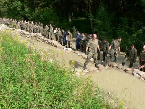 Bundeswehrsoldaten schlichten Sandsäcke zu einem Fangedamm auf, um austretendes Sickerwasser hinter einem Deich zu stoppen | W. Vogel, KBR Erding