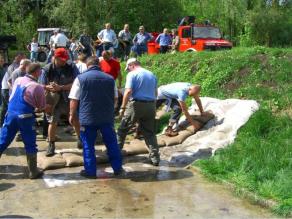 Einsatzkräfte verteidigen einen Hochwasserschutzdeich mit Sandsäcken.