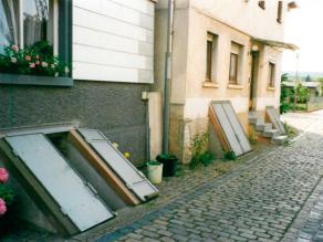 Zwei aneinander grenzende Häuser, die beide einen Kellerabgang besitzen. Diese können durch Klappen, welche wie eine Art Flügeltür aussehen, abgedichtet und verschlossen werden.