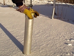 Ein Metallrohr mit Maßeinteilung auf der Außenseite wird in den Schnee gesteckt und abgelesen.