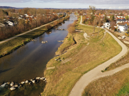 Drohnenaufnahme mit dem auf einer Seite der Mangfall zurückverlegten Deich und die Gewässeraufweitung, vor und nach der Deichrückverlegung schließen so wie auf der anderen Mangfallseite wieder gewässernahe Deiche an.