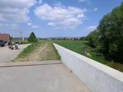 Hochwasserschutzmauer an einer Brücke, die in den daran angrenzenden Deich übergeht.