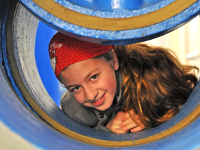 Ein Mädchen blickt durch einen großen Abwasserschieber.