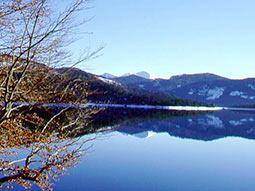 Walchensee im Winter, See mit Bergen im Hintergrund, die sich im Wasser spiegeln.