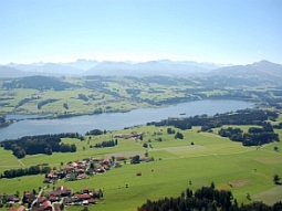 Die Luftaufnahme zeigt den Rottachsee inmitten der nördlichen Ausläufer der Allgäuer Alpen. Das Absperbauwerk liegt in der rechten, oberen Bildecke.