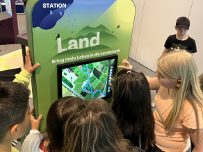 Schülerinnen und Schüler stehen vor der Station Land.