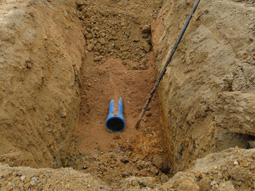 Verlegung einer Trinkwasserleitung im offenen Rohrgraben auf einer Baustelle