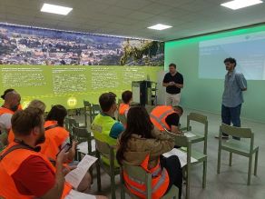 Teilnehmer der Sommerakademie im Informationszentrum der WUN-Bioenergie, auf Stühlen sitzend, die den Ausführungen der beiden Kollegen des LfU, Abt. Landesagentur für Energie und Klimaschutz (LENK) folgen.