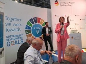 Einige der Delegationsteilnehmer auf dem Vortragspanel des German Water Partnership e.V.(GWP); die Präsidentin des GWP stehend in Diskussion mit den Teilnehmern (sitzend) .