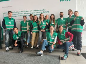 Gruppenfoto das im Zusammenhang des Firmenbesuches der WILO SE aufgenommen wurde, Teilnehmern der Sommerakademie und zwei Betreuerinnen vor einem Banner der WILO SE.