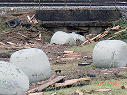 Silageballen und Holz haben einen Durchlass eines Bahndammes verklaust. In der Folge kam es zu einer Überströmung der Bahngleise und der Ablagerung von Treibgut.