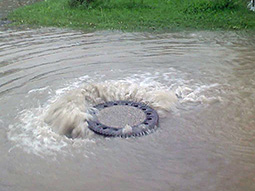 Wasser tritt aus einem Kanal aus und verursacht eine Überflutung der umliegenden Straßen und Häuser.